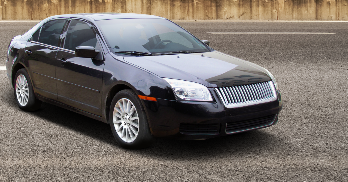 Black Mercury sedan parked on asphalt road.