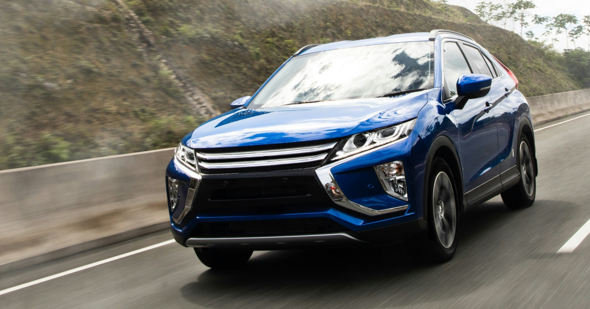 Blue Mitsubishi Eclipse Cross driving on a highway with a mountain in the background.