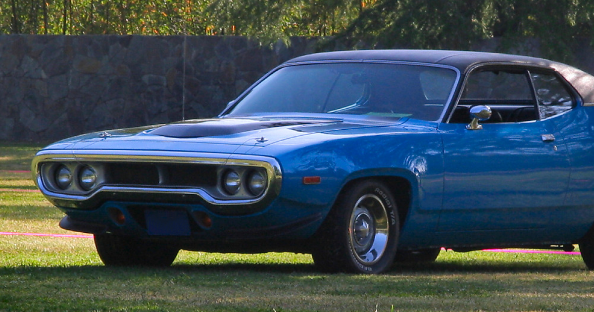 Blue classic Plymouth Road Runner car parked on grass.