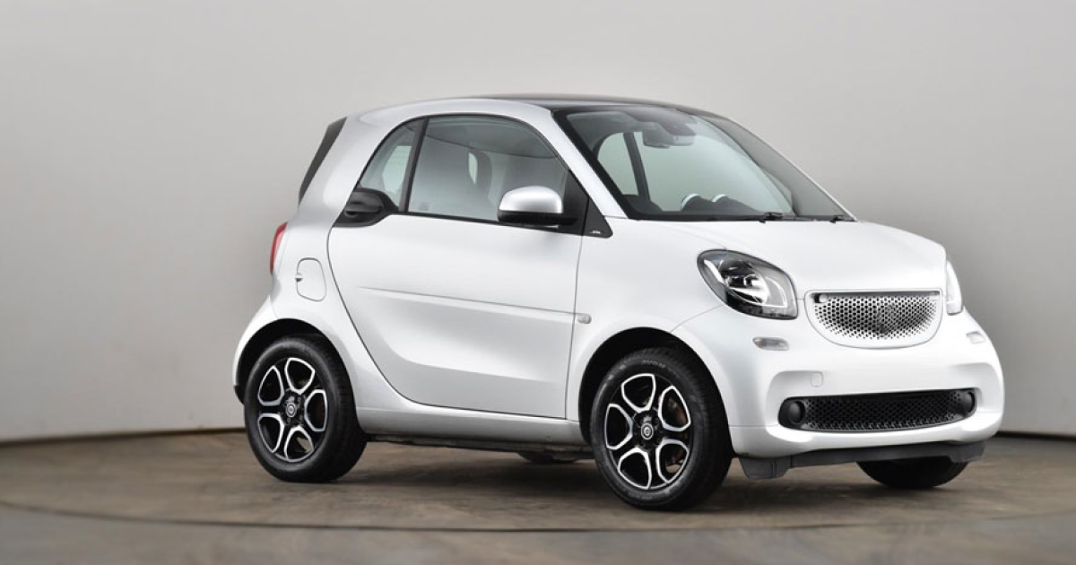White Smart car on a studio background; small, two-door vehicle with black accents.