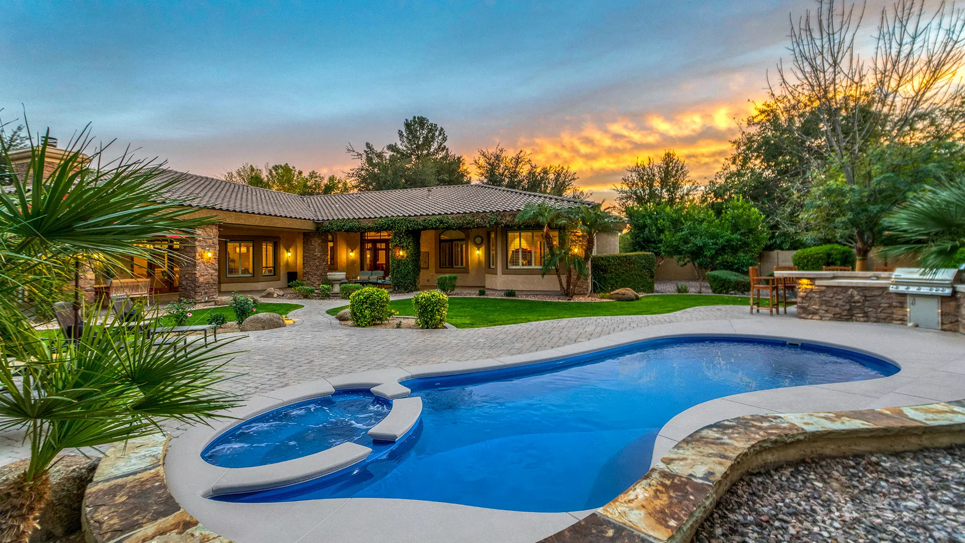 Pool in a white-walled courtyard, with lounge chairs and lush greenery. Steps lead into the blue water.