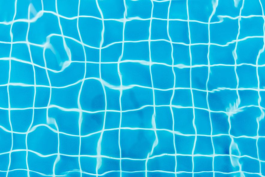 Blue pool water with white grid tiles visible through the rippling surface.