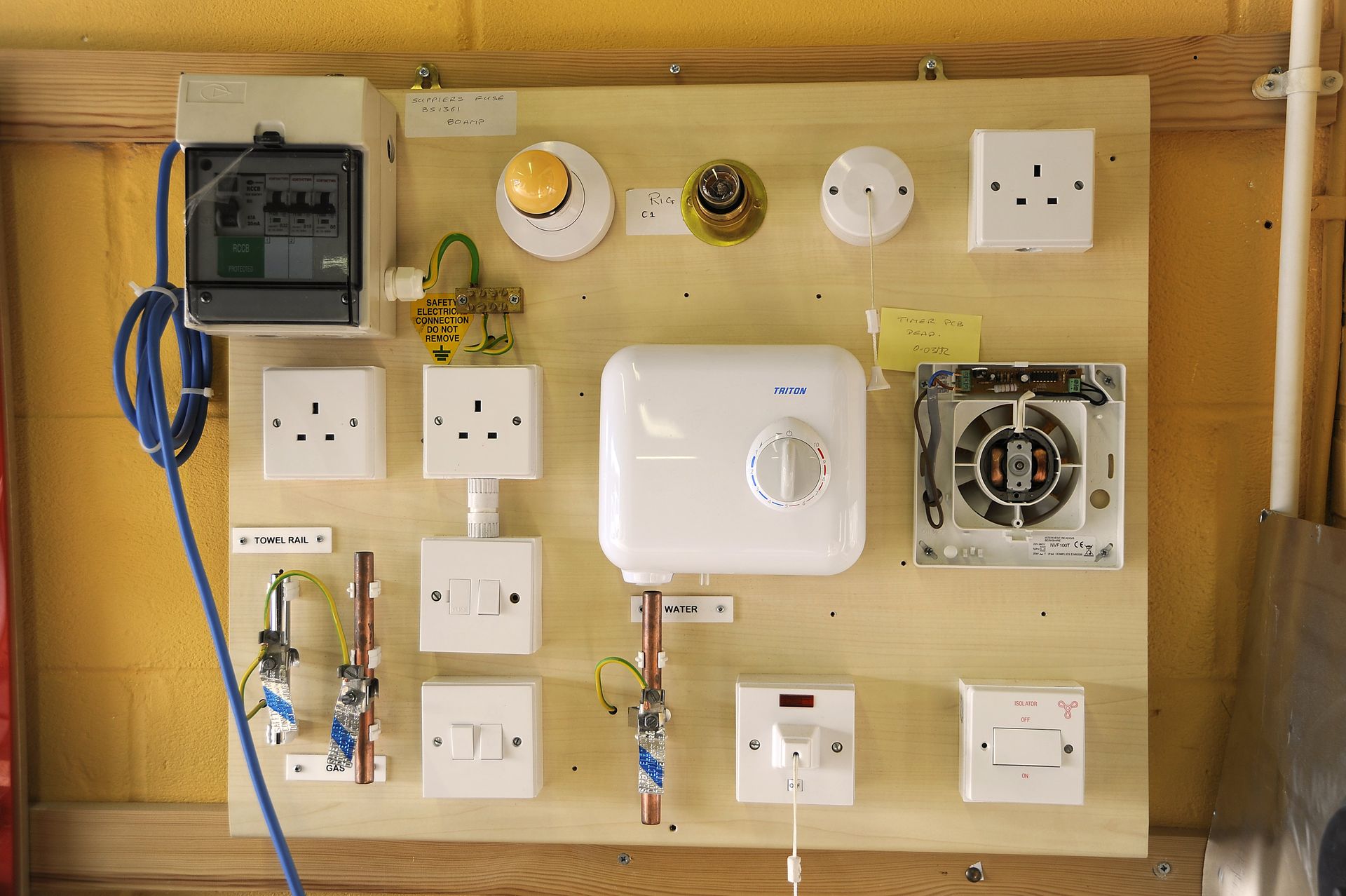 A wooden board with electrical equipment on it is hanging on a wall.