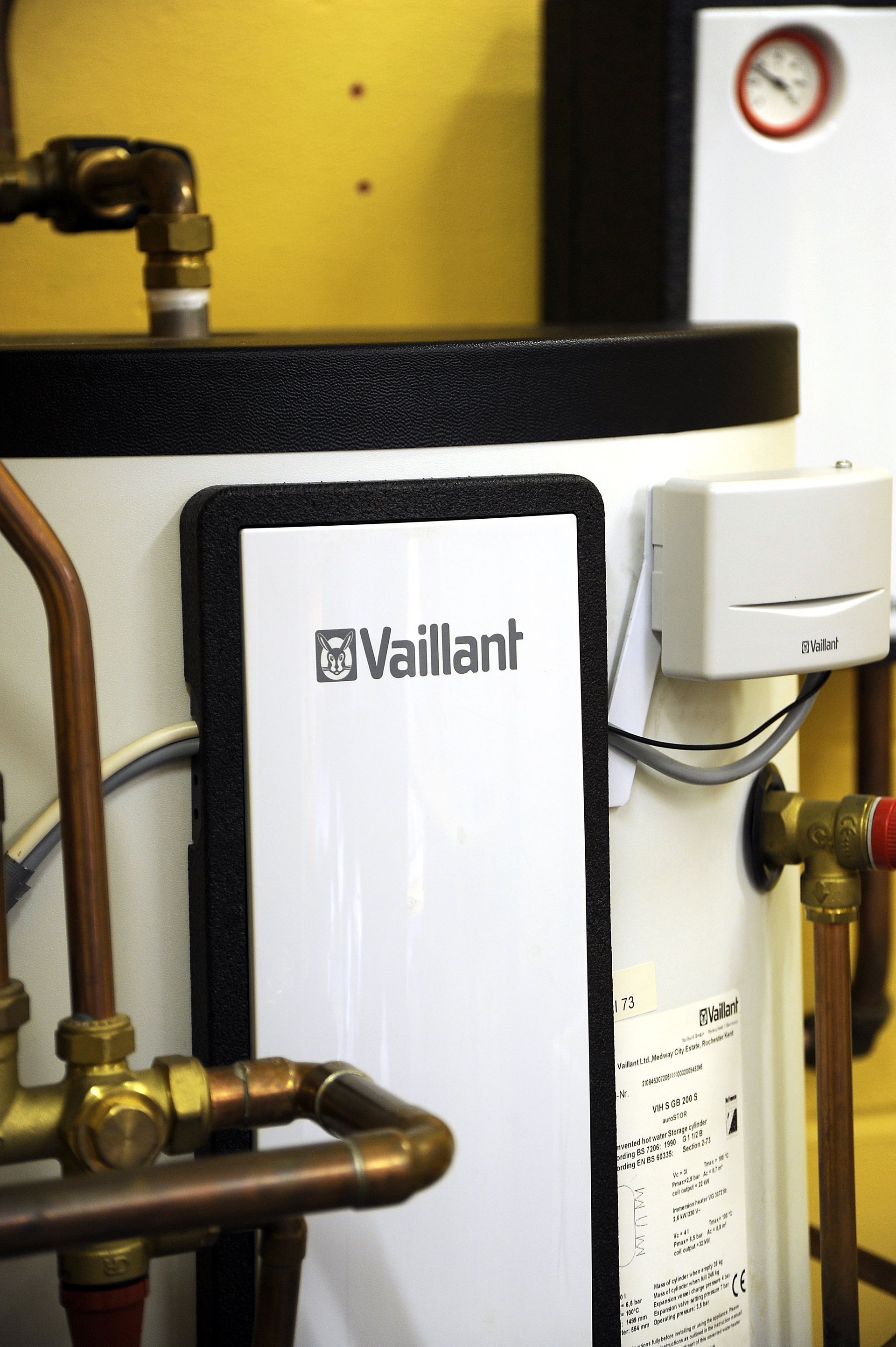 A vaillant water heater is surrounded by pipes and a clock
