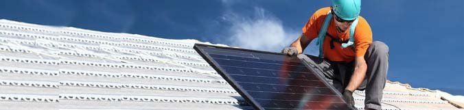 A man is installing a solar panel on a roof.