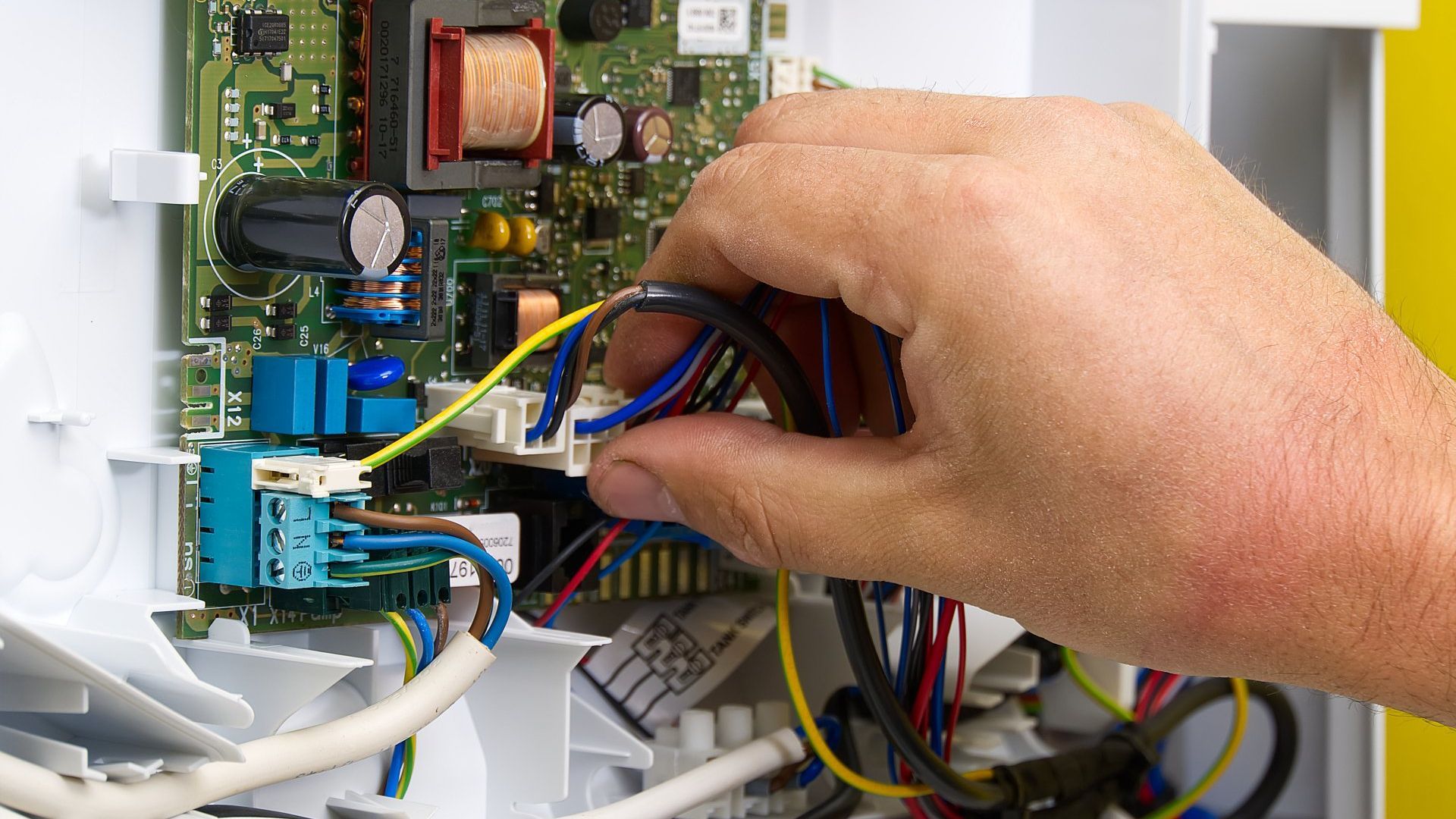 A person is working on a motherboard with wires coming out of it.