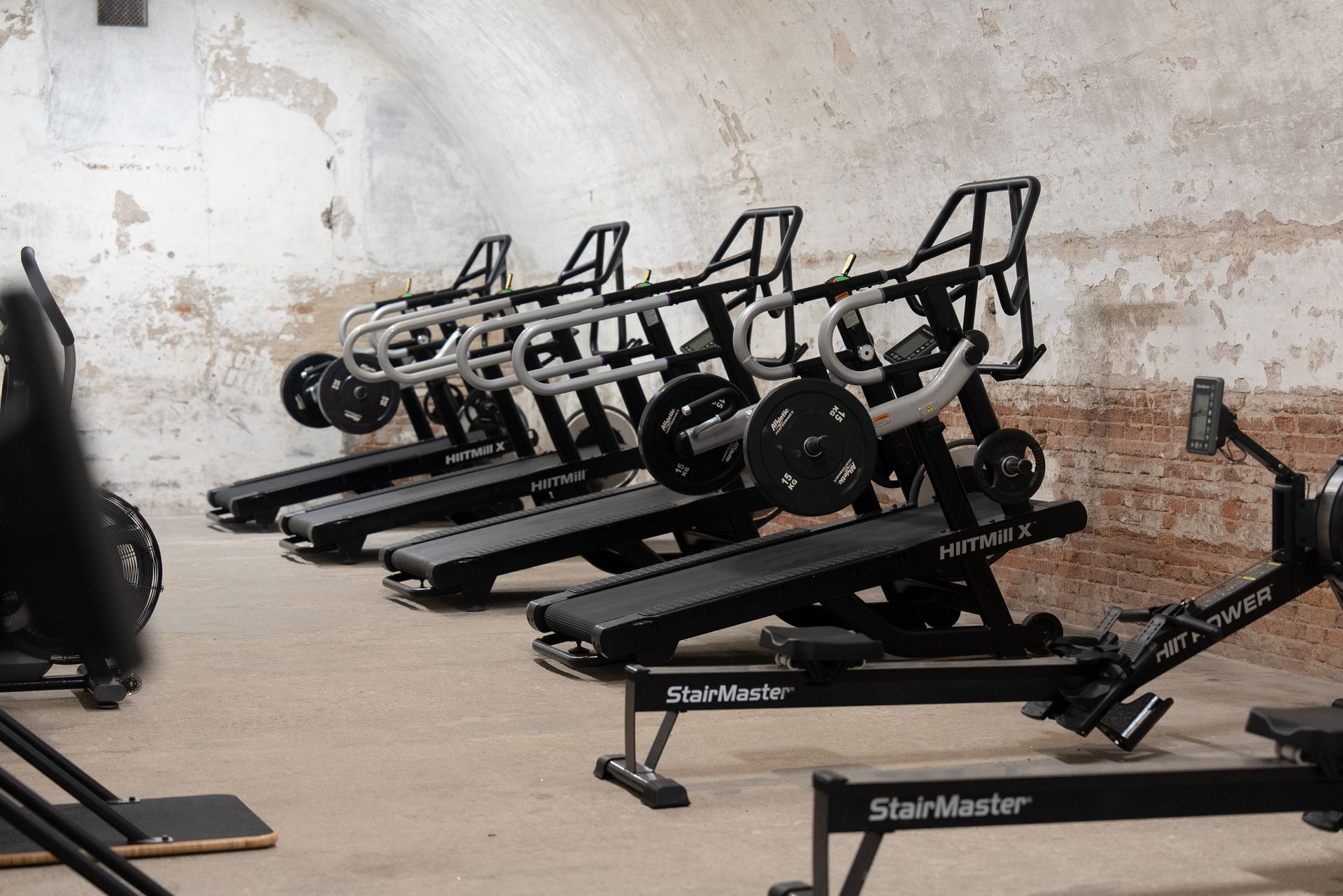 Black StairMaster stair-climbing exercise machines lined up in a worn gym space.
