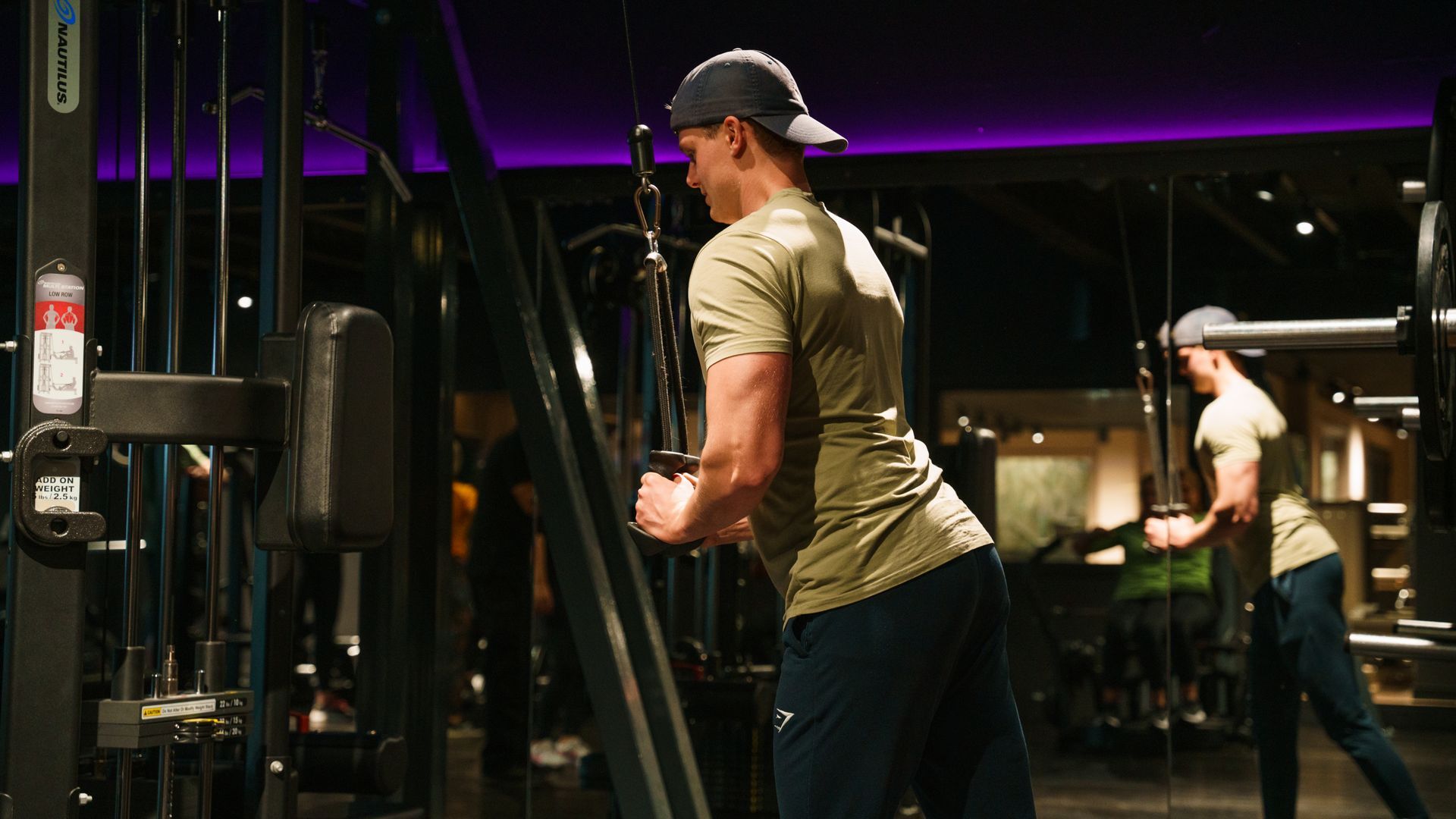 Modern gym with rows of exercise machines, black flooring, and large windows