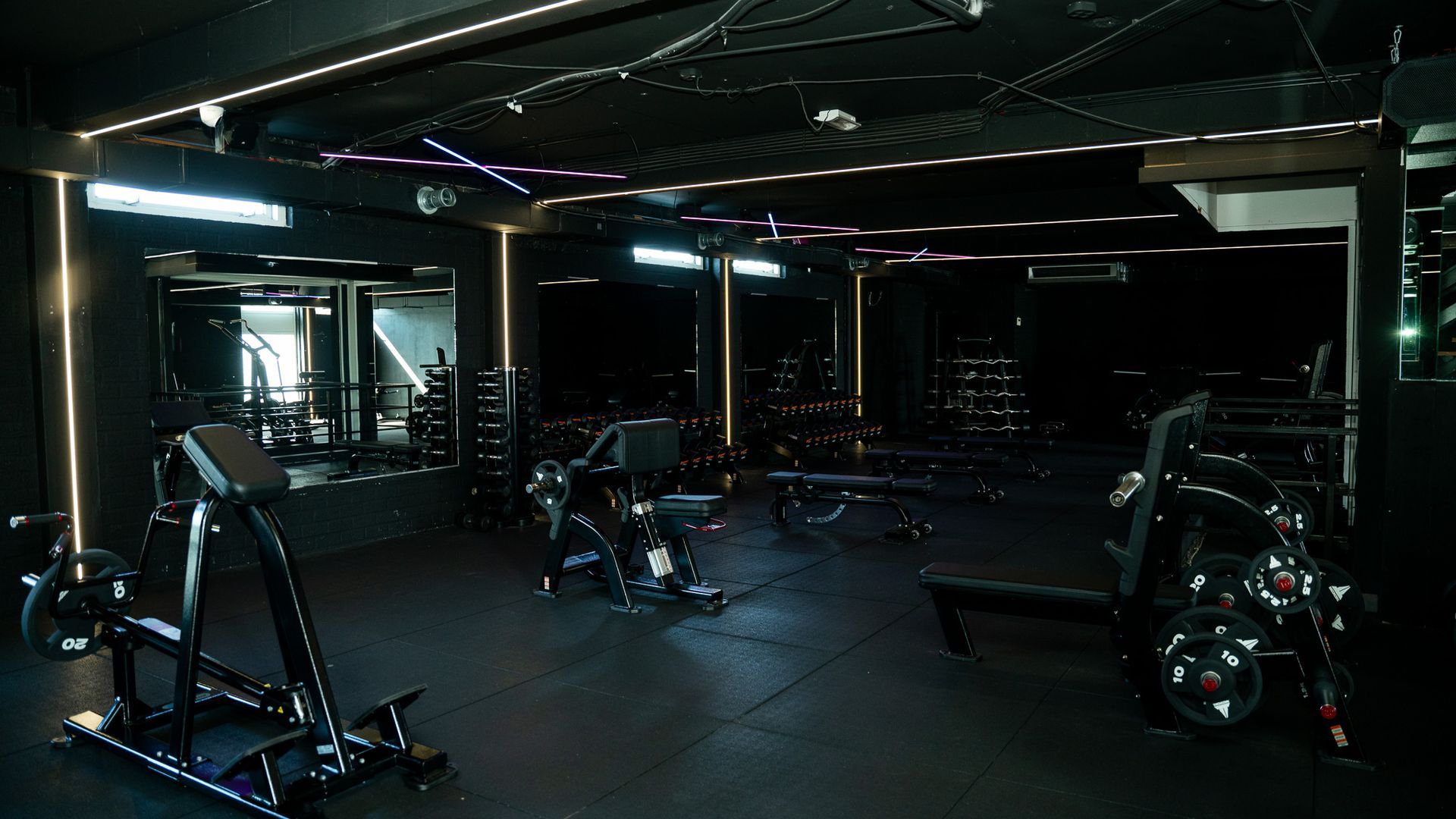 Dark, empty modern gym with weight machines and reflective windows at night