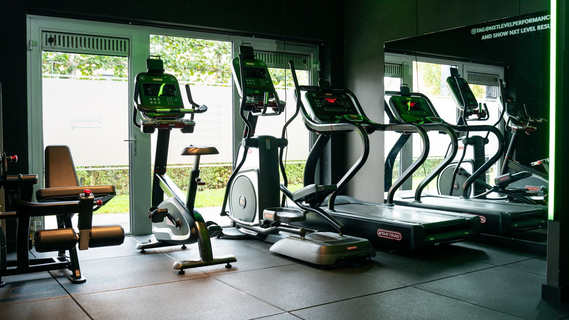 Empty gym with treadmills and exercise bikes by large windows