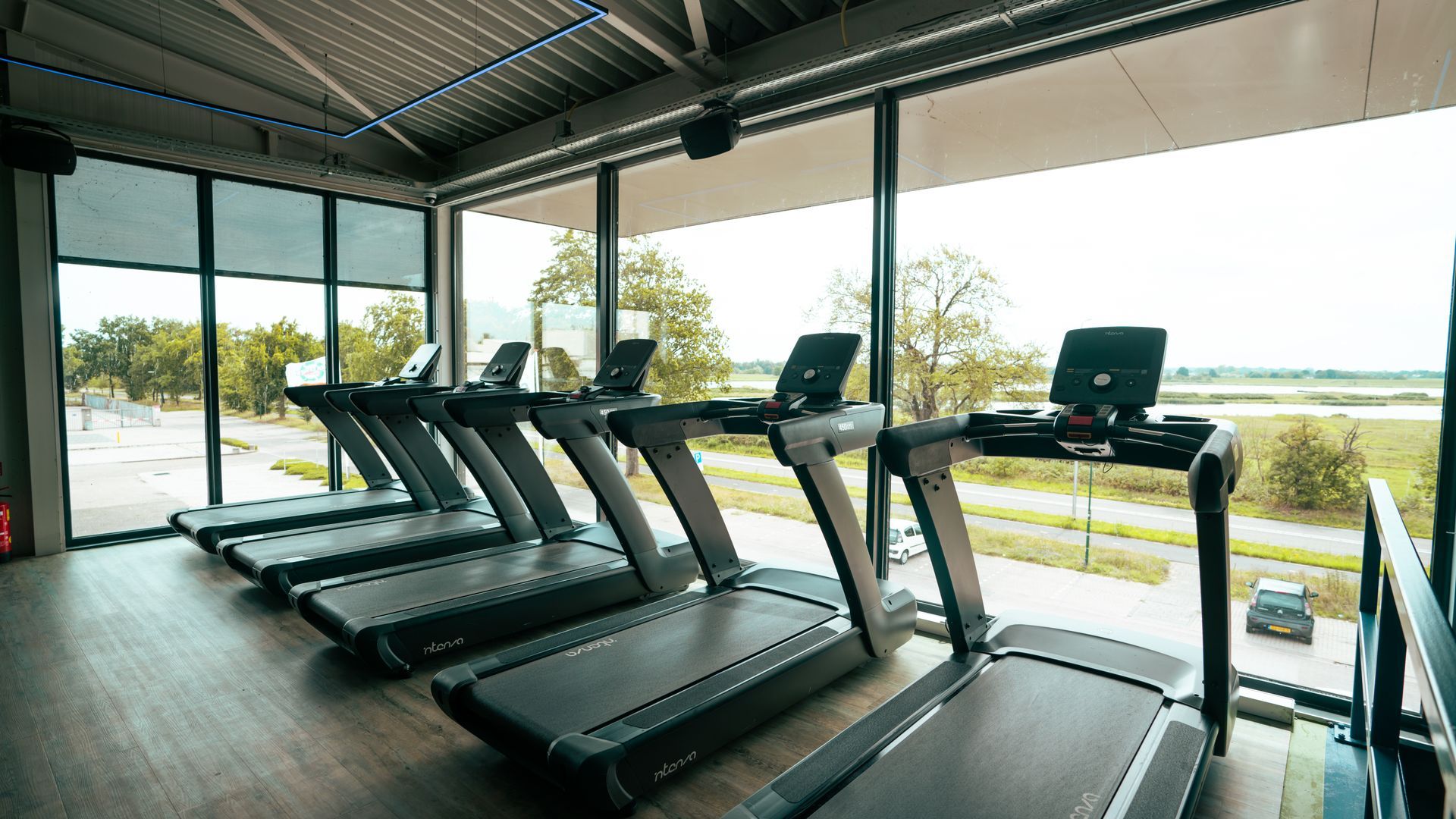 Modern gym with treadmills facing large windows and a waterfront view