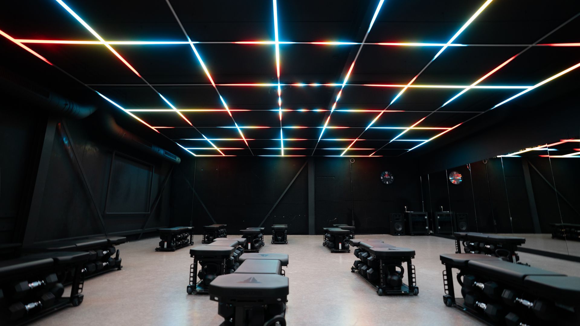 Empty dark classroom with rows of desks and neon strip lights on the ceiling