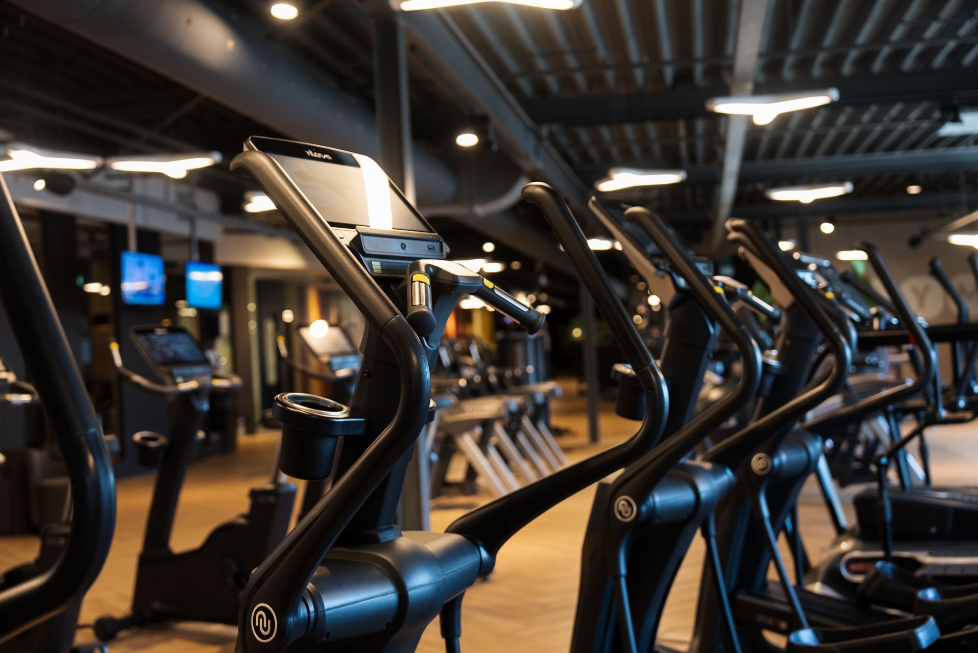 Row of elliptical machines in a dimly lit gym