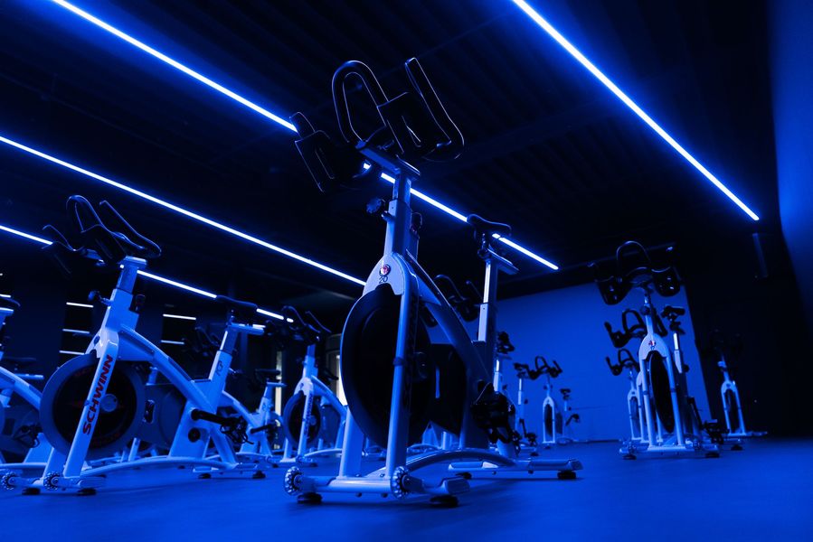 Blue-lit gym interior with stationary bikes and other workout equipment