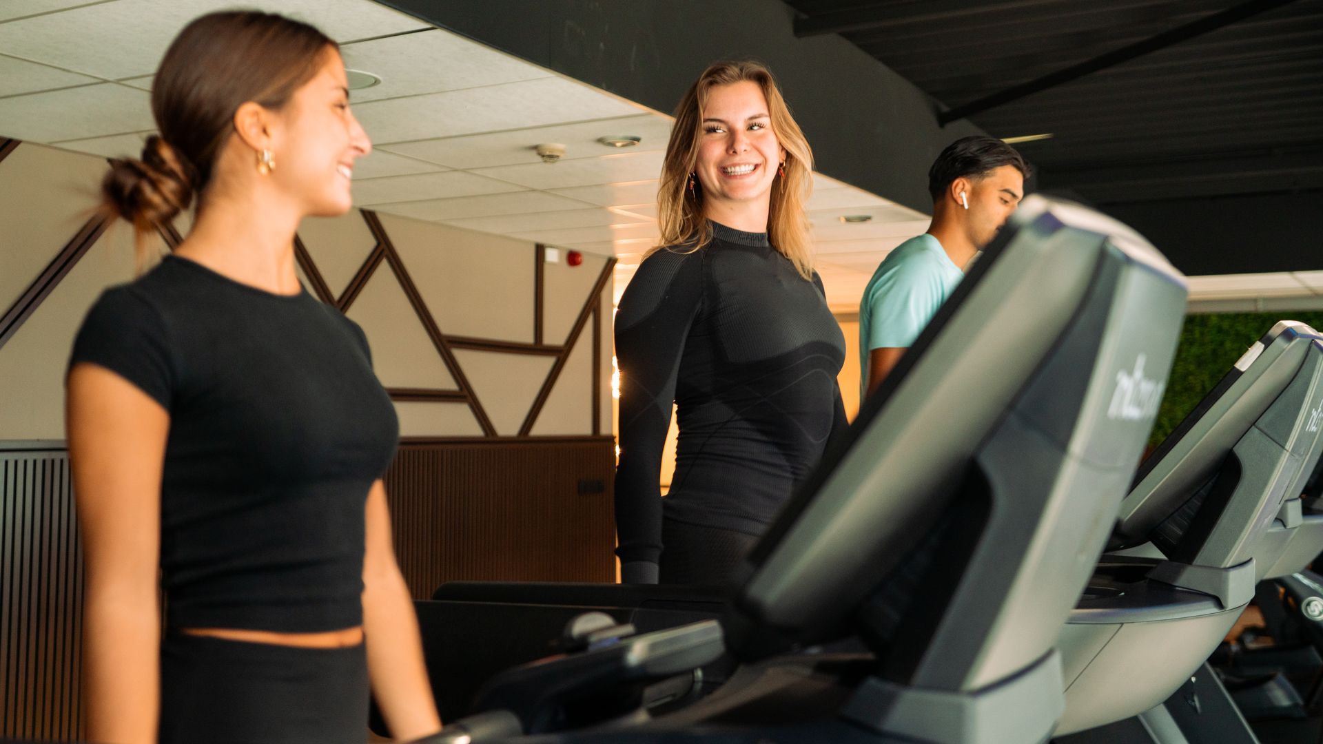 People on treadmills in a gym, with one woman smiling in the foreground