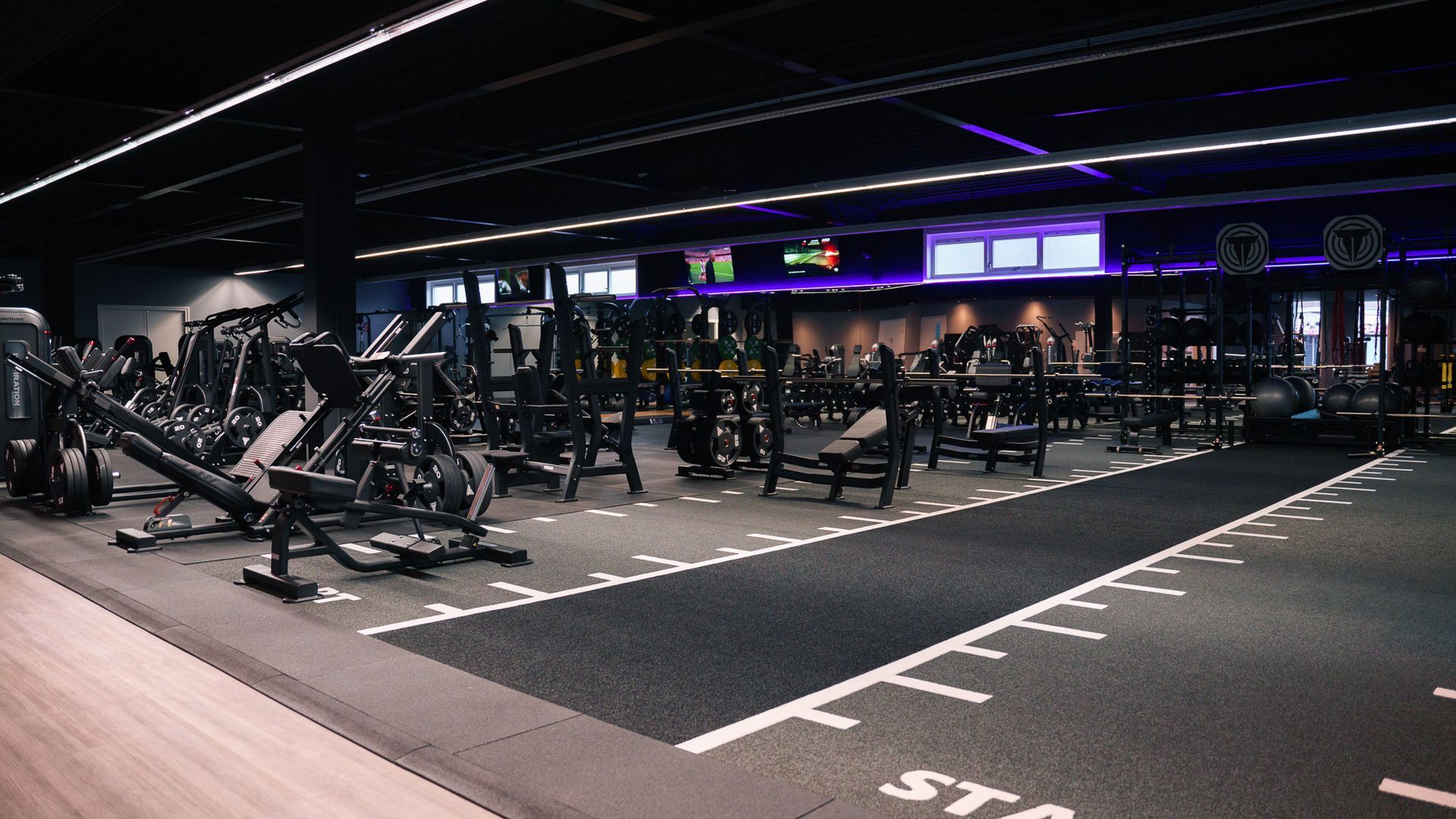 Empty modern gym with rows of exercise machines and dark lighting