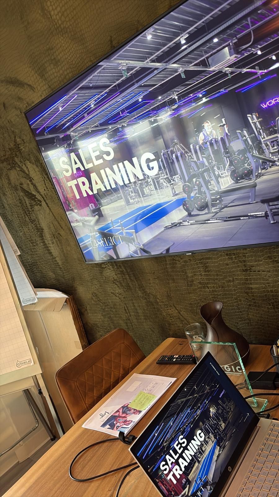 Sales training display in a modern office with a laptop, books, and a cityscape screen backdrop