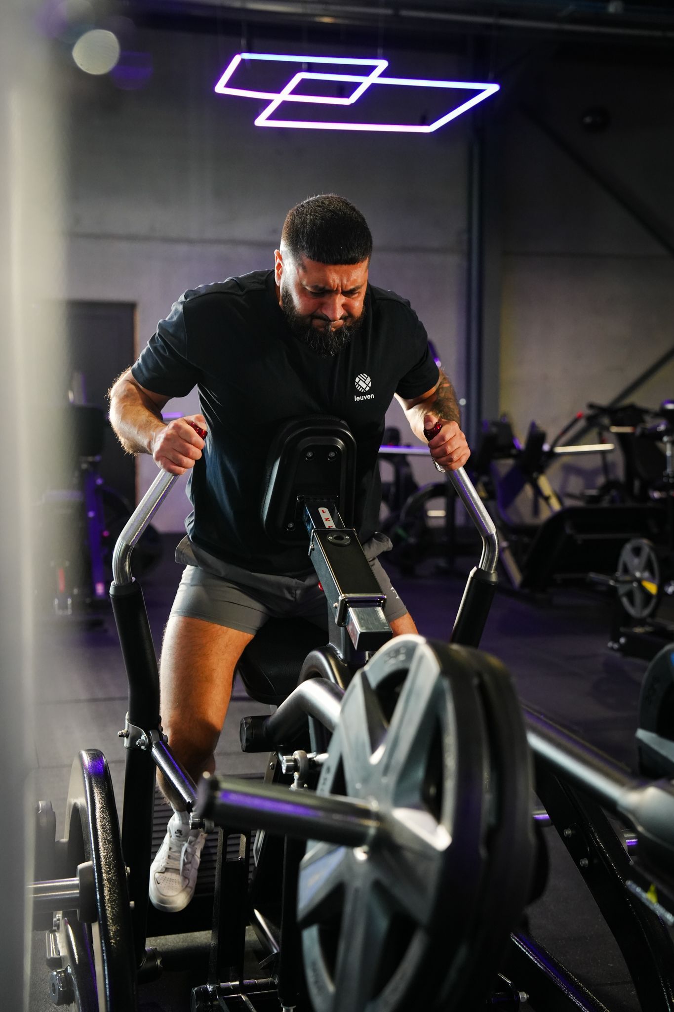 Man using a rowing machine in a dimly lit gym, focused on exercise.