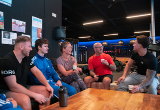Five people sitting and talking around a wooden table in a dimly lit lounge