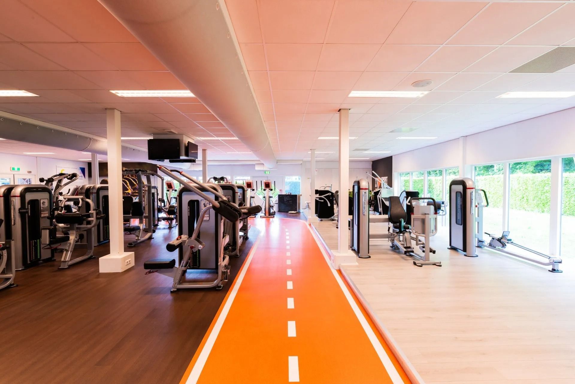 Bright gym interior with an orange running track and exercise machines along both sides