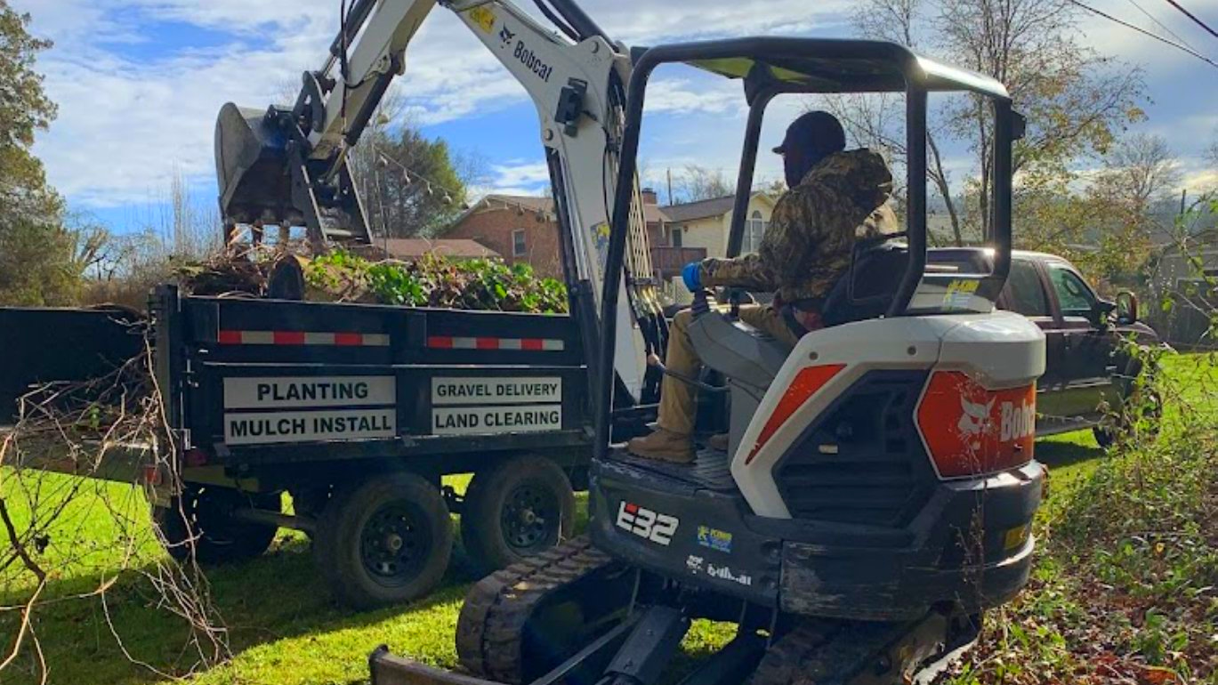excavator loading brush on a dump trailer