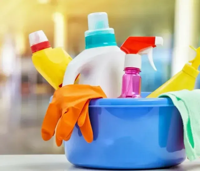 Un recipiente azul lleno de productos de limpieza y guantes.