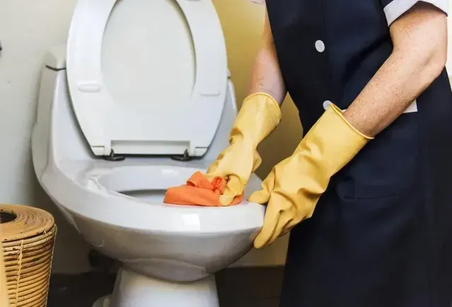 Una persona con guantes amarillos está limpiando un baño