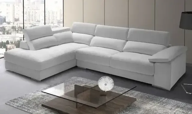 Un sofá seccional blanco está sentado junto a una mesa de café de vidrio en una sala de estar.