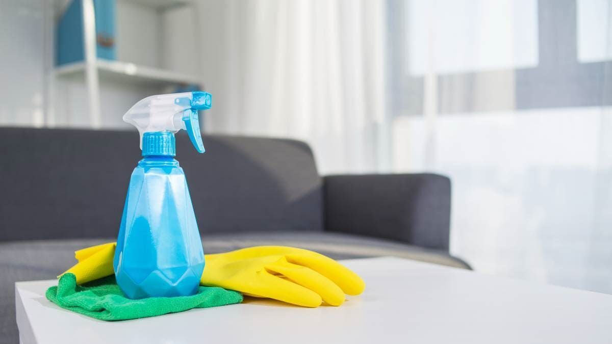Una botella de spray y guantes están sobre una mesa en una sala de estar.