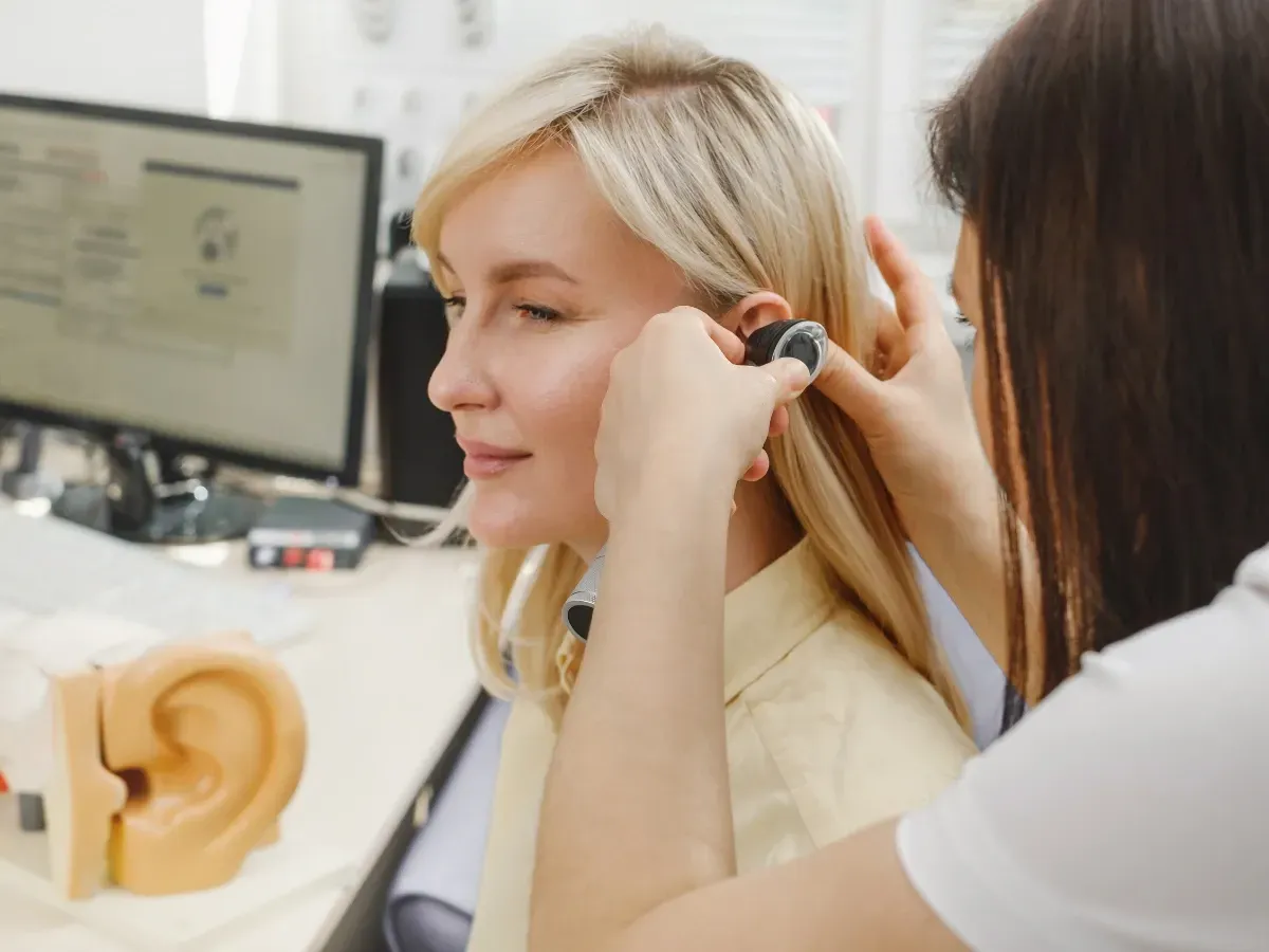 A hearing specialist adjusting a patient’s hearing aid for a precise fit and better sound quality.