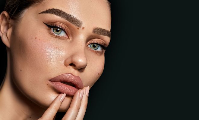 A close up of a woman 's face with her hand on her face.