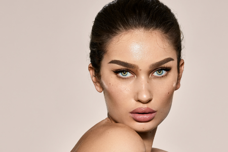 A close up of a woman 's face with a ponytail and blue eyes.