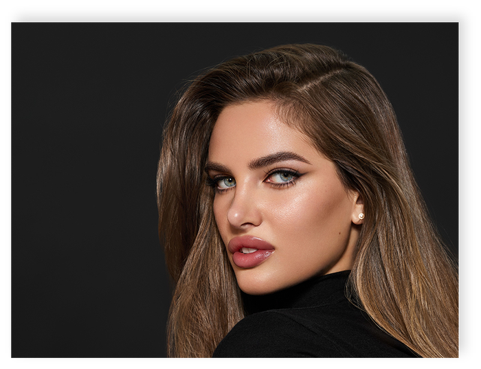 A woman with long hair is wearing a black turtleneck and looking over her shoulder.