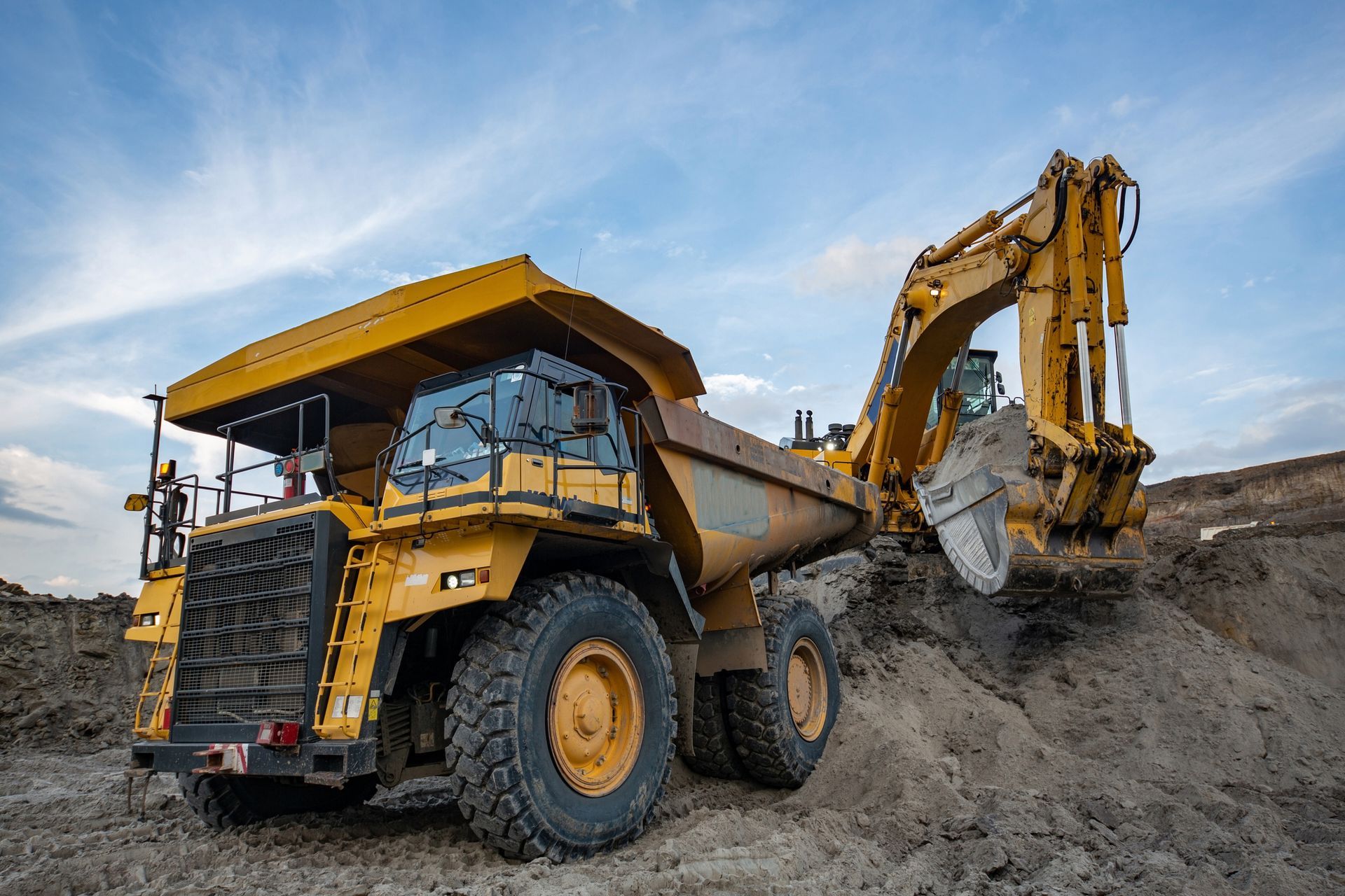 Mining vehicle loads soil and stone material into a truck at opencast coalmine.
