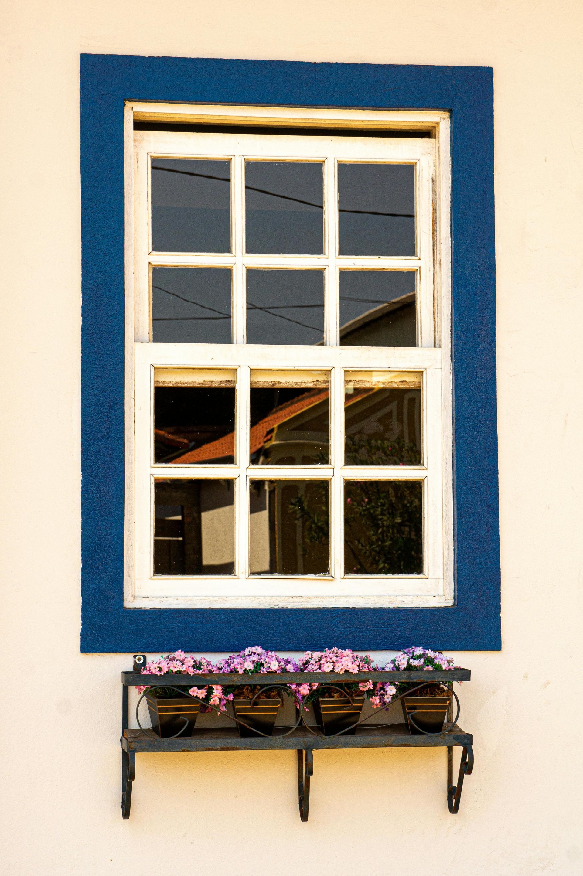 A window with a blue frame and a shelf with flowers on it