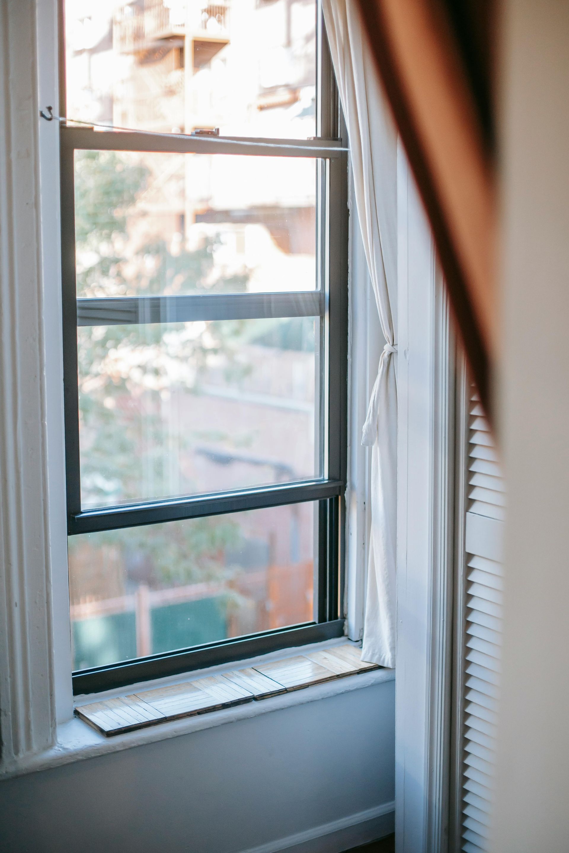 A close up of a window with a white curtain in a room.