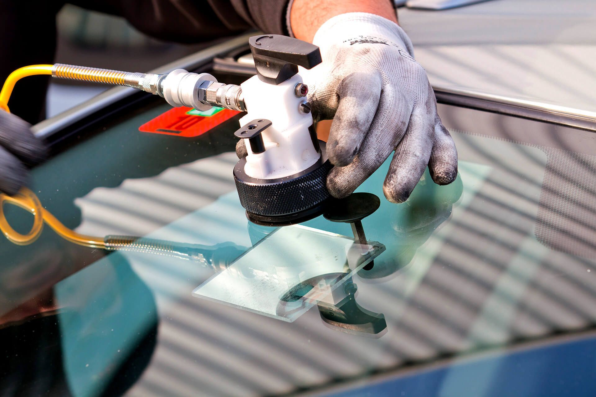 A person is repairing a windshield with a tool.
