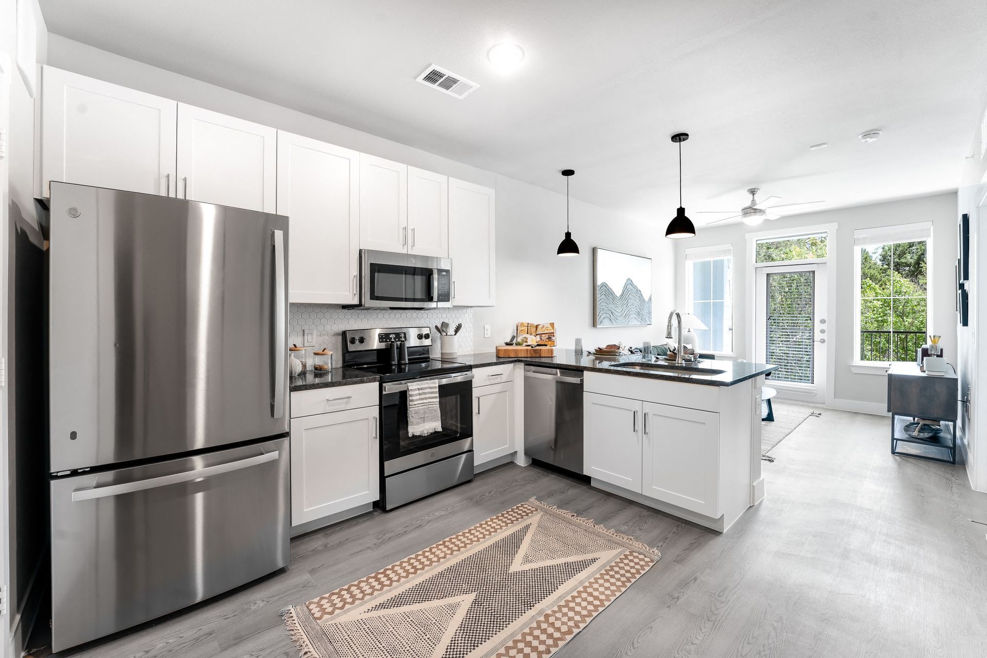 A kitchen with stainless steel appliances and white cabinets at The Bennett, offers pet-friendly apartments.