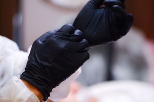 A person is putting on a pair of black gloves.