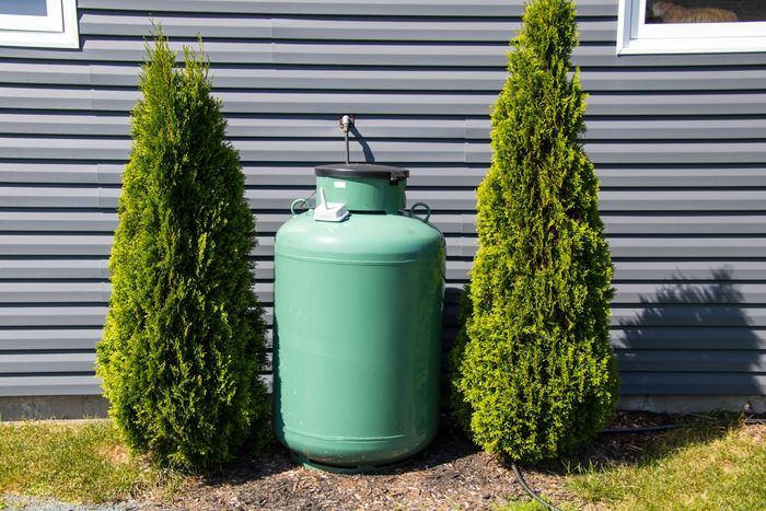 A large white propane tank is sitting in front of a house