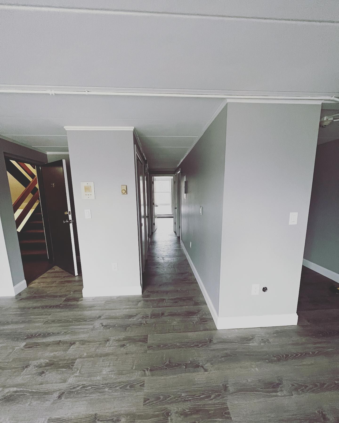 A long hallway with wooden floors and white walls in a house.