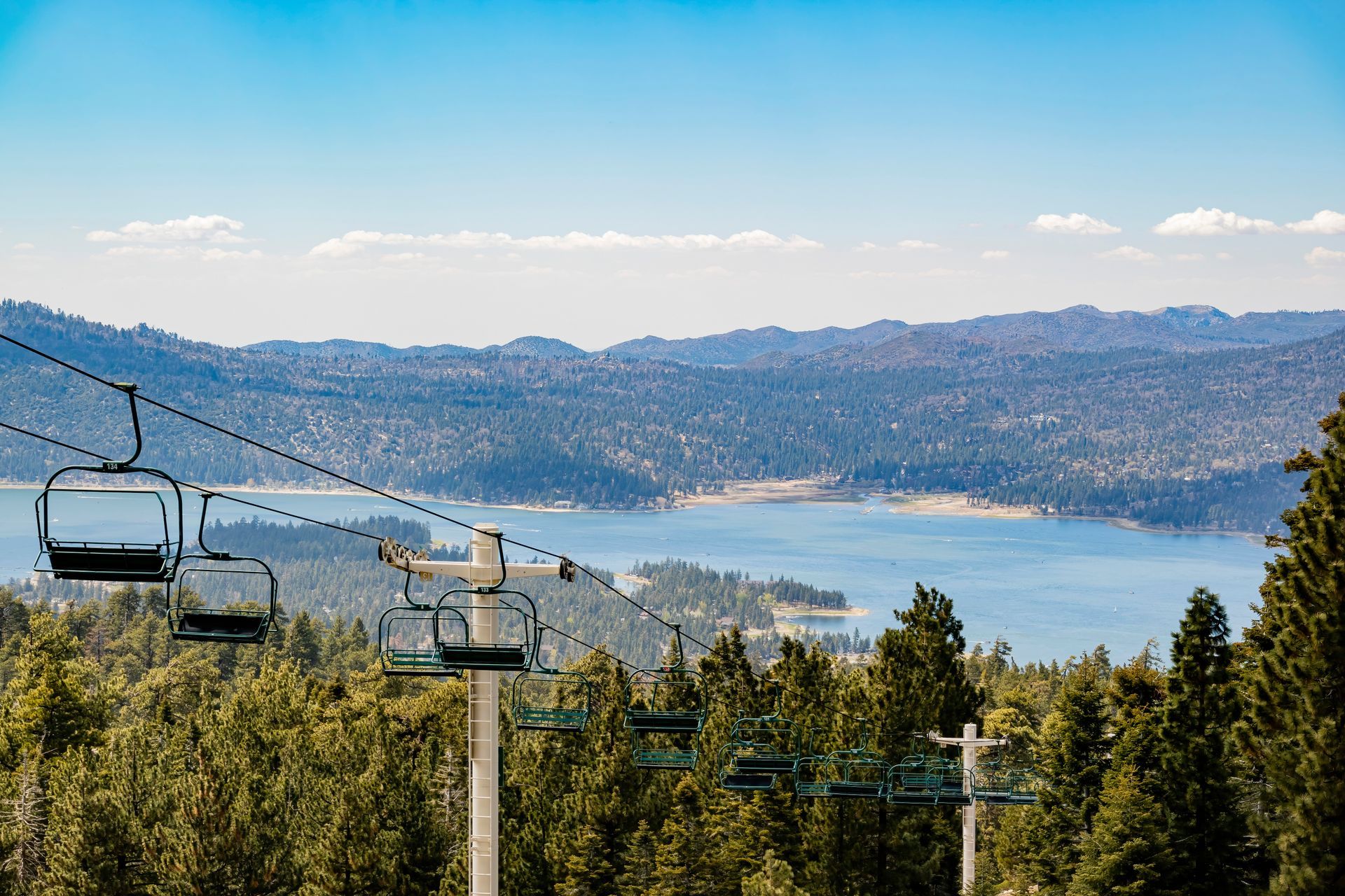 A ski lift with a view of Big Bear Lake and mountains.