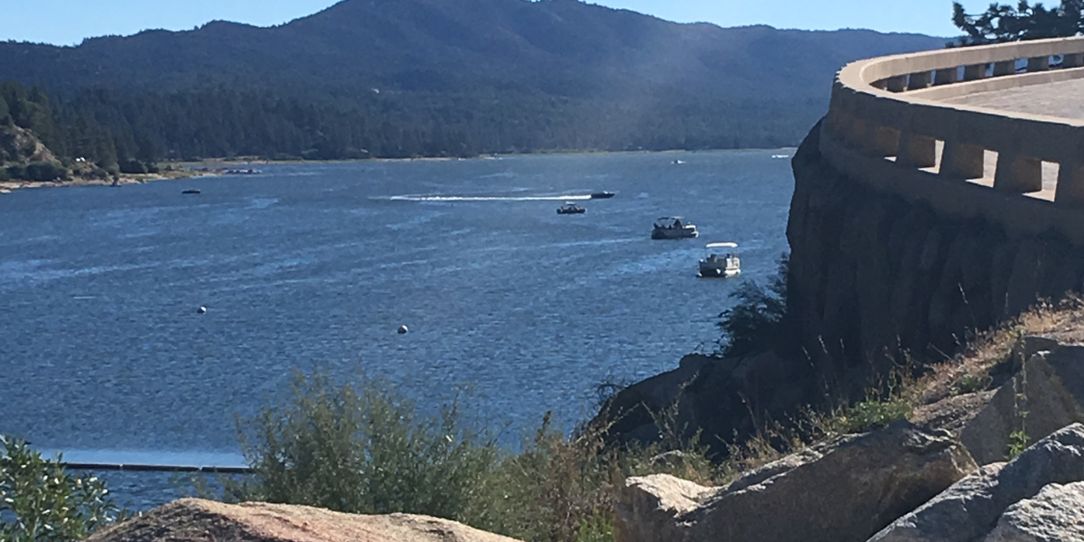 A view of a lake from a cliff with boats in it.