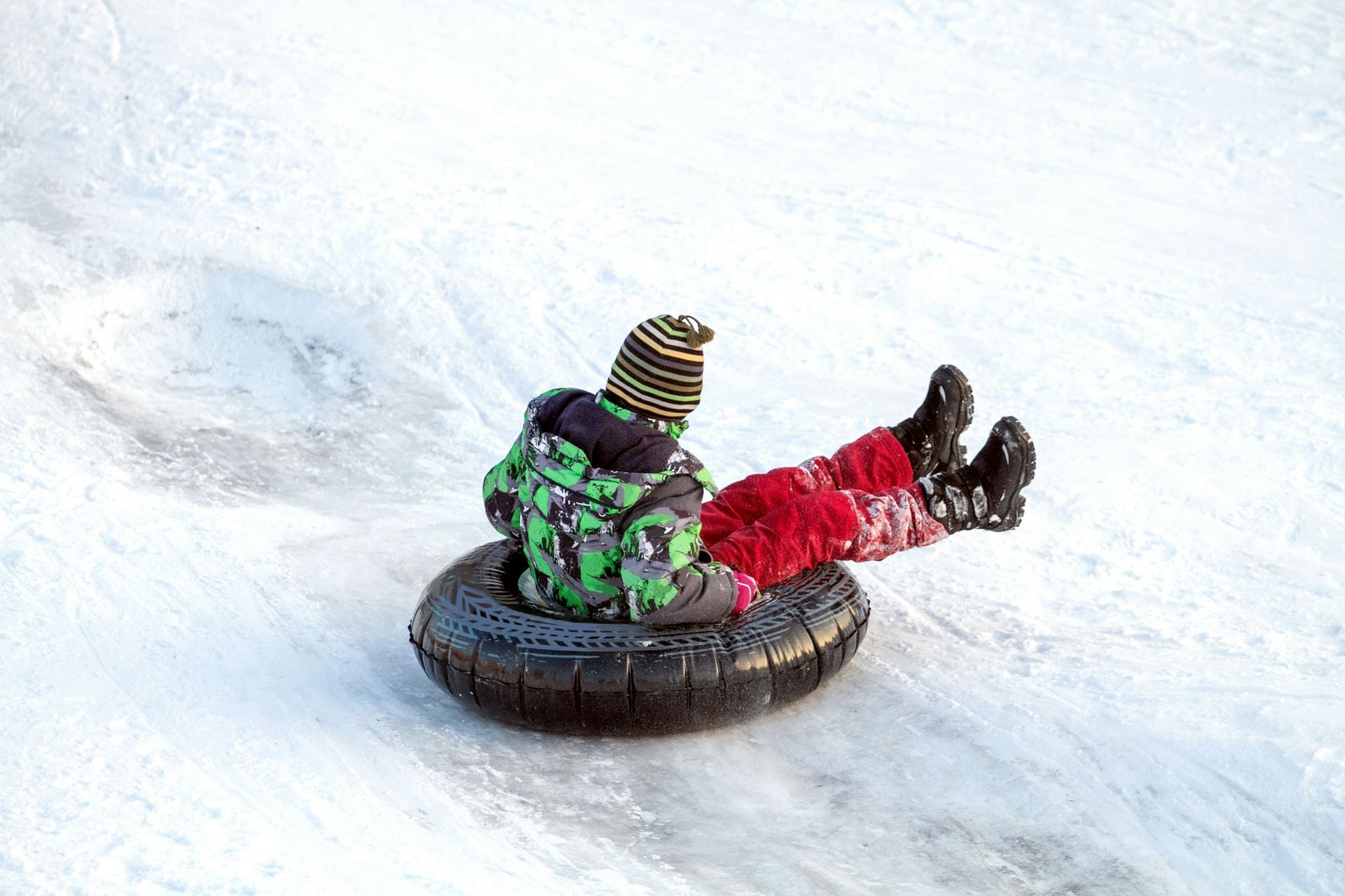 A child is riding a snow tube down a snow covered hill.