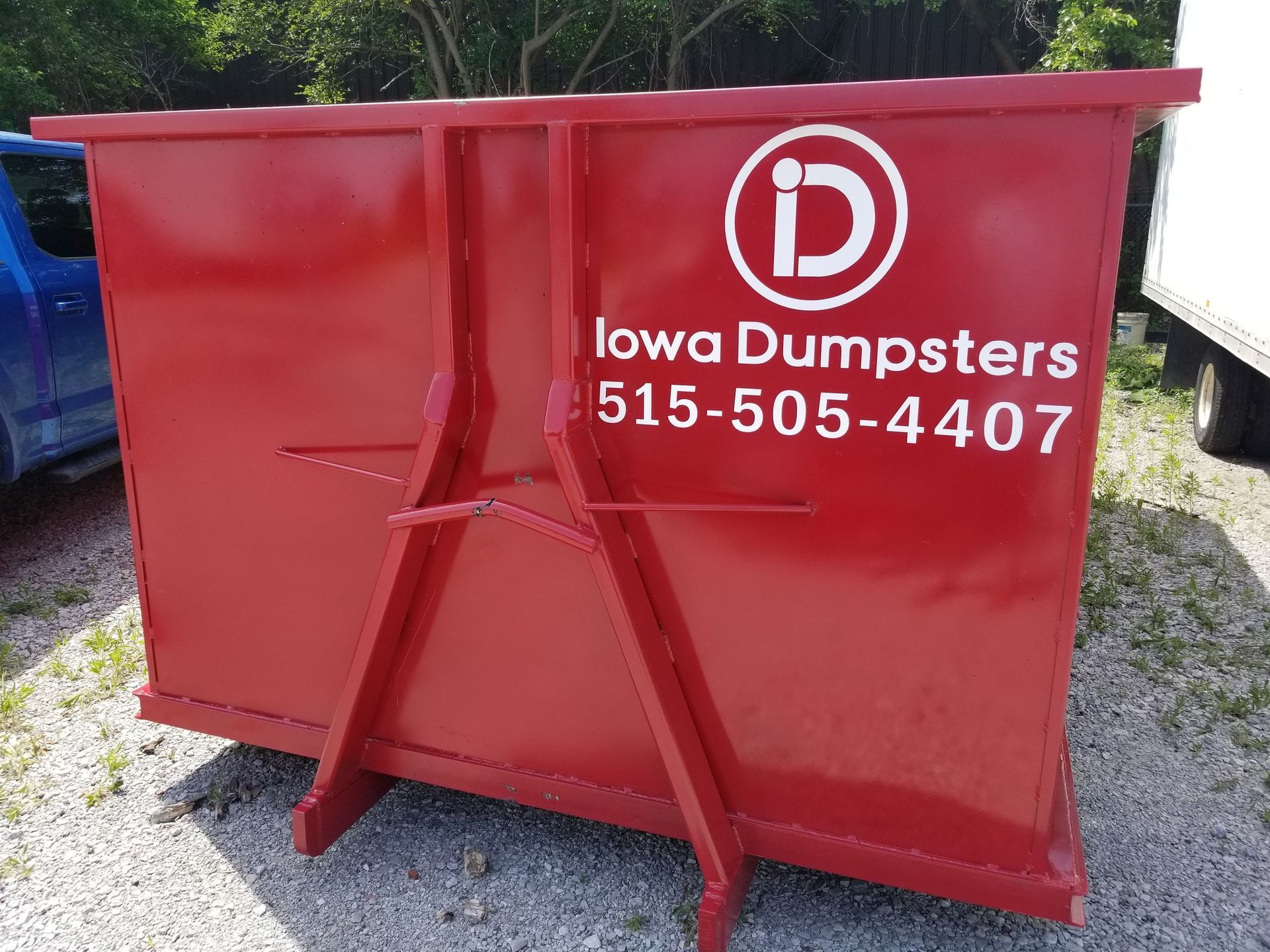 Red Iowa Dumpsters container with the company logo and phone number, outdoors.