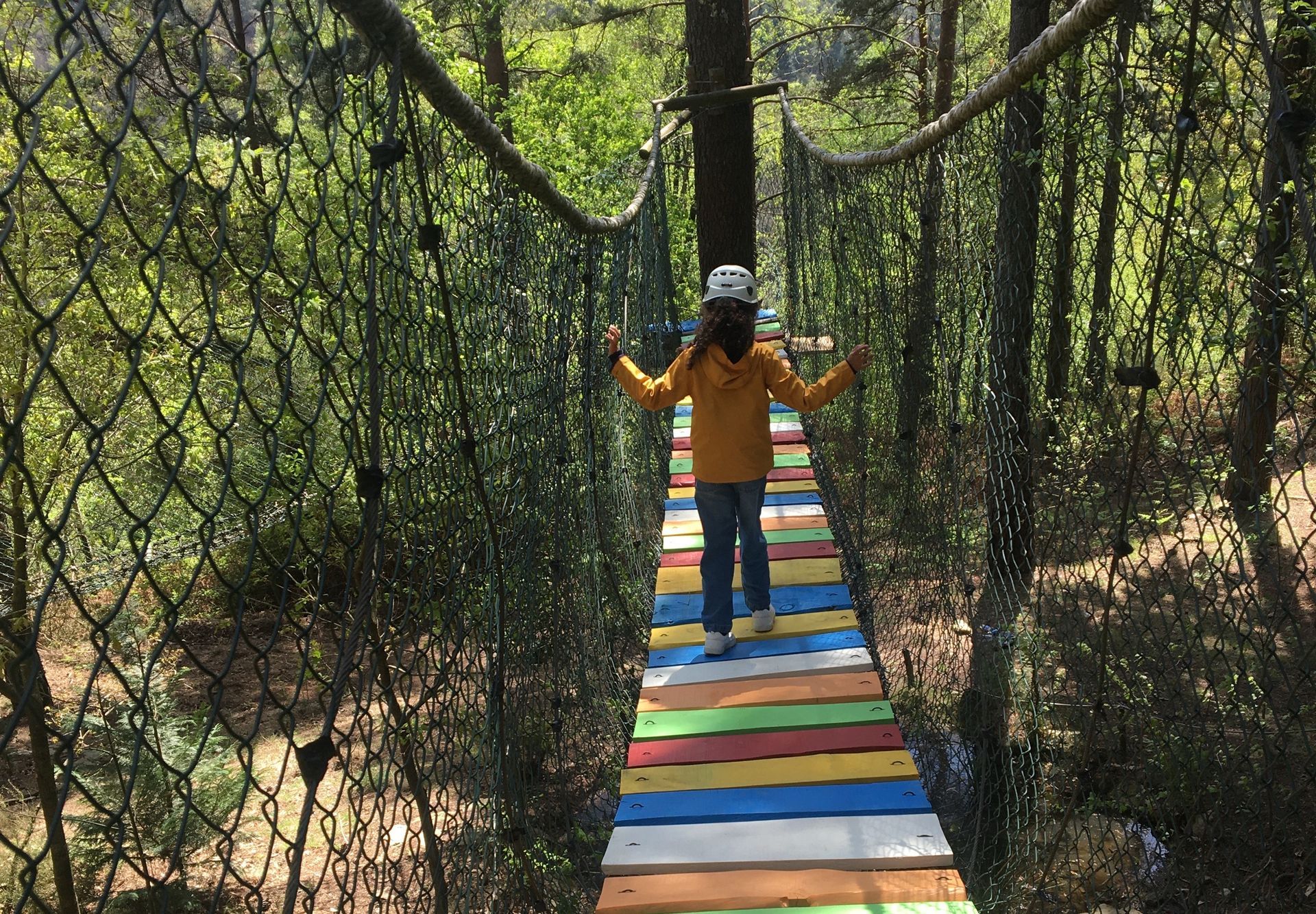 menina percorre curiosa a ponte colorida no bosque encantado no pena aventura