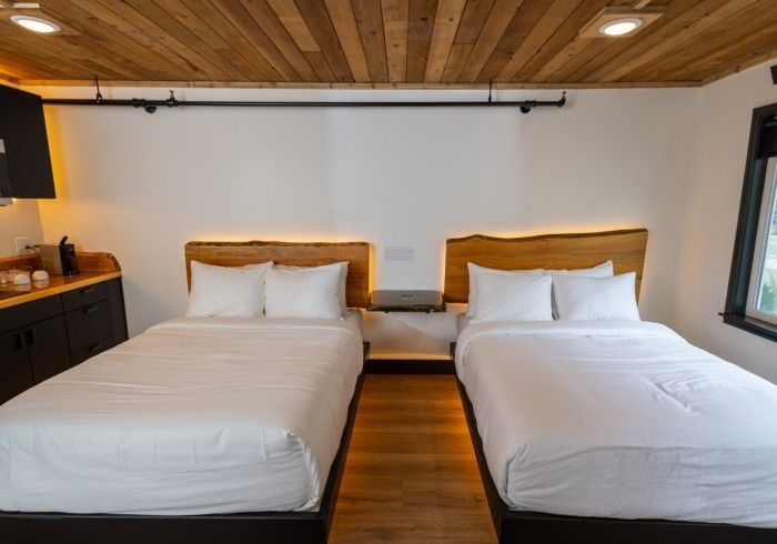 A hotel room with two beds and a wooden ceiling.