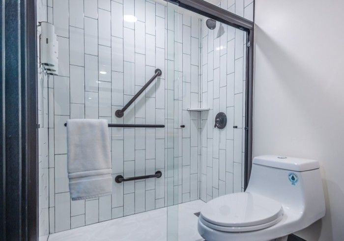 A bathroom with a toilet , shower , and towel rack.