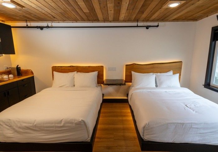 A hotel room with two beds and a wooden ceiling.