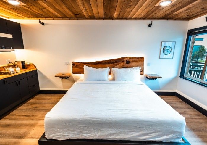 There is a bed in the middle of the room with a wooden headboard.